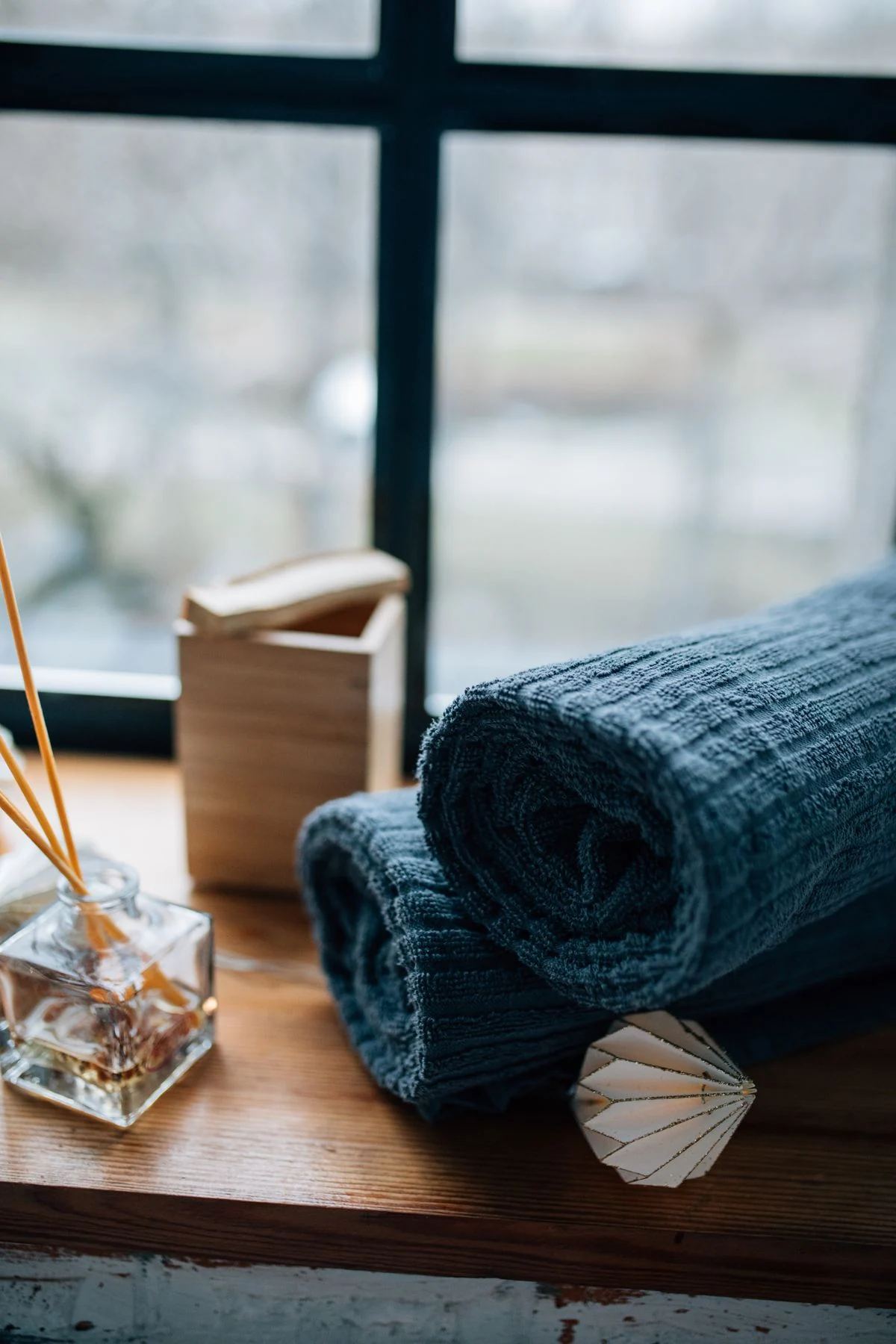 Rolled blue textile fabric on wooden desk with decorative items and window view