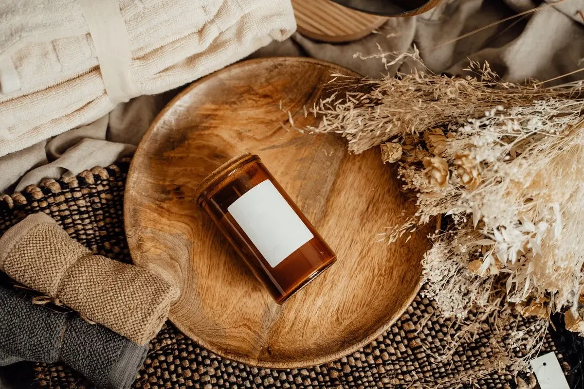 Amber glass bottle with white label on wooden bowl surrounded by natural fibers and textiles