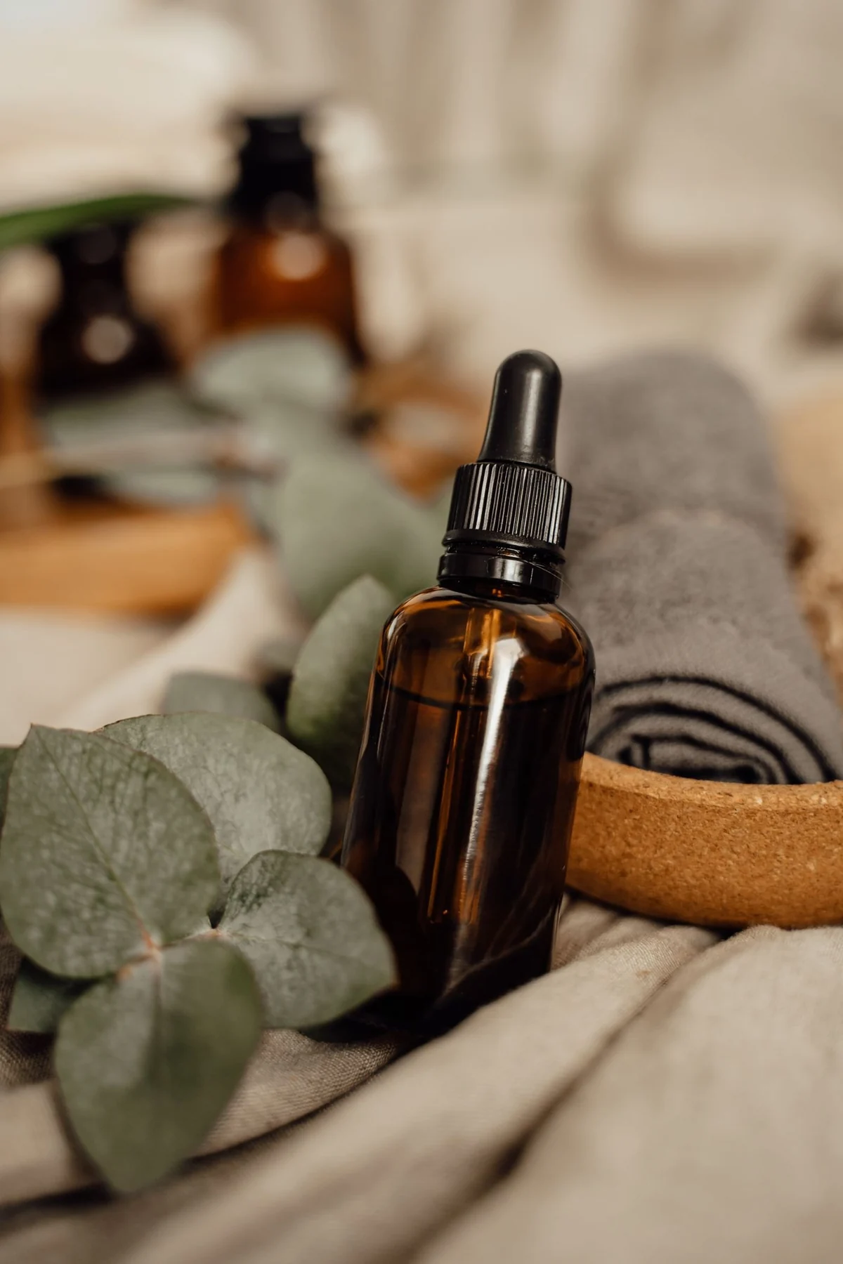 Amber glass dropper bottle with eucalyptus leaves and spa accessories on linen fabric