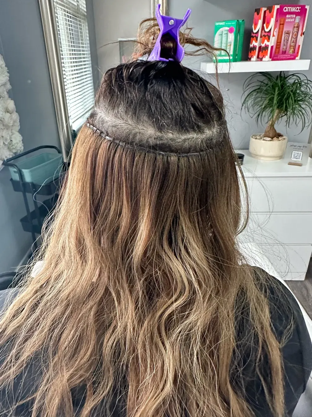 Hair extension application showing weft method on long brunette hair with highlights