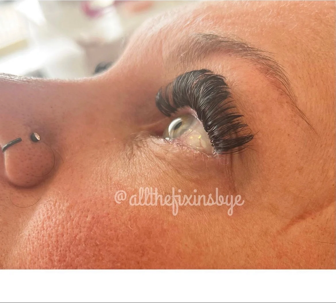 Close-up of dramatic black eyelash extensions applied to a client's eye during a beauty procedure