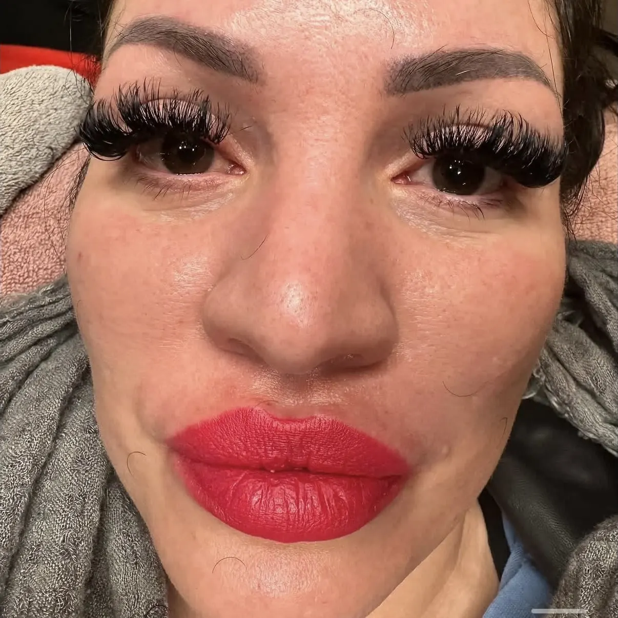 Close-up of person's face with bold red lipstick and dramatic black false eyelashes