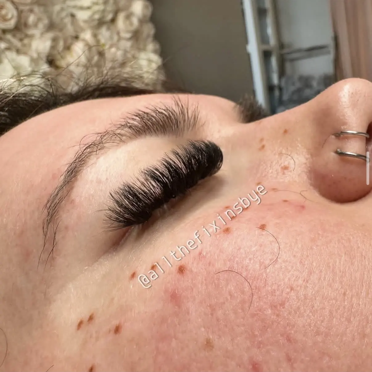 Close-up of dramatic black false eyelashes applied to closed eyelid during beauty procedure