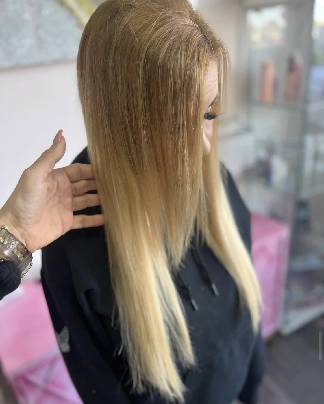Long blonde hair being held up to display length and texture in salon setting