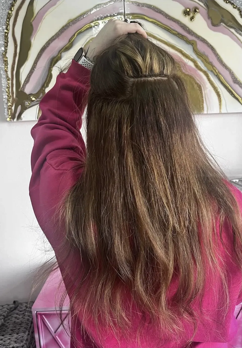 Person with long brown hair wearing pink jacket viewed from behind