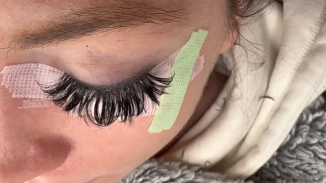 Close-up of false eyelashes being applied with under-eye protective pad
